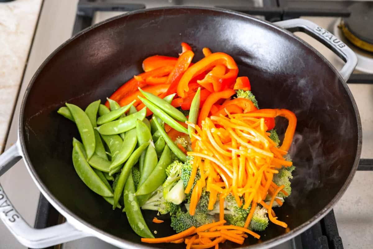 Veggies cut up and thrown in vegetable oil in a wok.