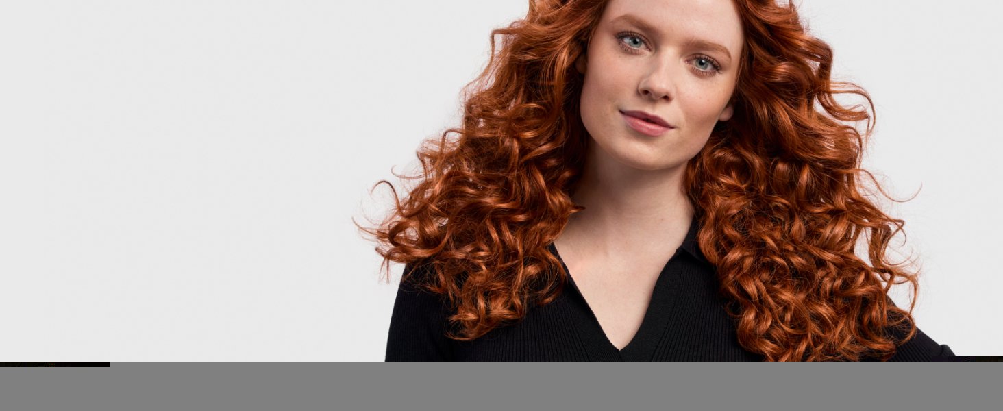 Model with red wavy hair styled into 80’s curls